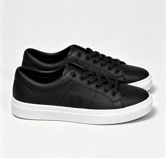 These appear to be black leather Fred Perry tennis sneakers featuring a lace-up front and the brand's signature embroidered laurel wreath logo on the side.
